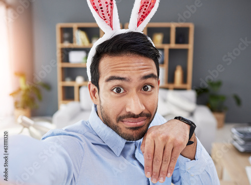 Bunny ears, holiday and selfie with a man and remote work on easter with creative job. Celebration, happy and male professional from Spain feeling silly and goofy with comedy rabbit hat in a home