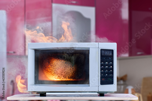 Electric fire from malfunctioning microwave with smoke and open flames in kitchen.