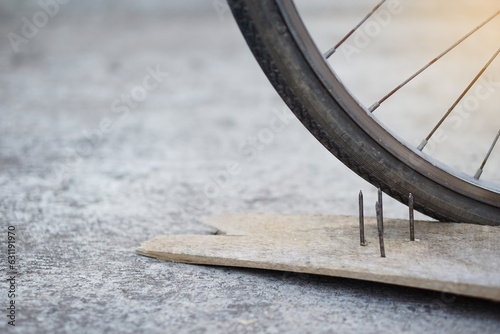 Close up nails on wood board and flat bicycle tire. Concept, unsafe , damage. Be careful and look around during cycling on the floor or risk places. Accident can be happened. 