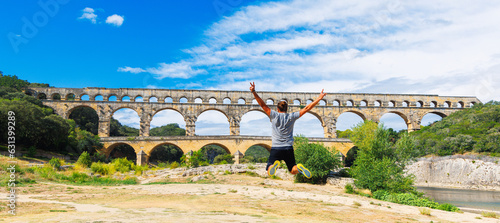 Pont du Gard and happy man tourist jumping- tour tourism, travel, vacation in France- Gard
