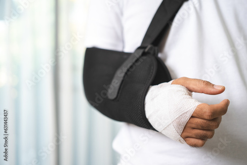 Social security and health insurance concept. Young Man suffer pain from accident fracture broken bone injury with arms splints in cast sling support arm in living room.