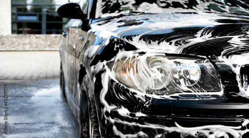 New black modern car sprayed with washing foam. Washing the car.