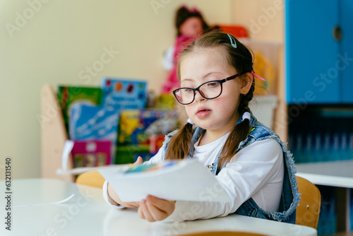 Cute little junior choolgirl with spesial needs sitting at desk at class. Welcome back to school. The new academic semester year start.