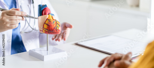 Cardiology Consultation treatment of heart disease. Doctor cardiologist while consultation showing anatomical model of human heart with aged patient talking about heart diseases.