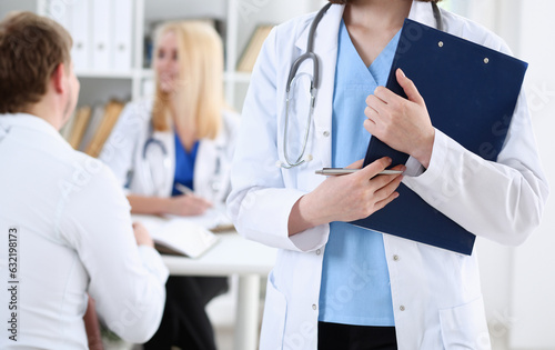 Female medicine doctor hand holding silver pen looking in clipboard pad closeup. Ward round patient visit check 911 medical calculation and statistics concept. Physician ready to examine patient