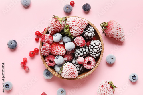 Bowl of different frozen berries on pink background