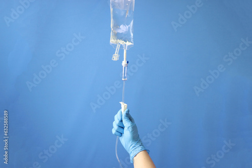 Professional opening the infusion set to delivery the drug thru intravenous infusion. Infusion set isolated in a blue background 