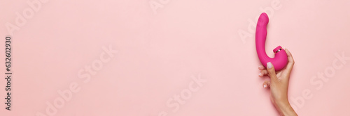 Banner. Female hand with vibrator, medical massager over pastel pink background. Image for sex shop. Concept of woman health, medicine, ad