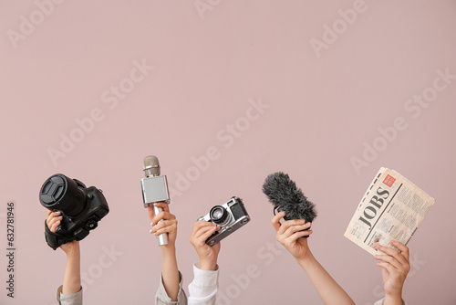 Female hands with newspaper, microphones and photo cameras on color background