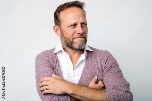 Lifestyle portrait photography of a man in his 40s scratching his arm due to atopic dermatitis wearing a chic cardigan against a white background 