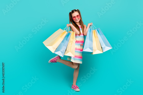 Full length photo of charming cheerful girl wear trendy clothes hand hold packages black friday price isolated on blue color background