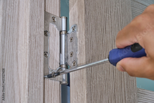 Repair and installation door hinges with screwdriver.