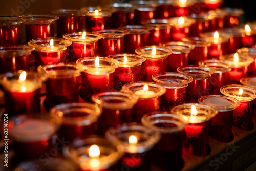 Rows of burning votive candles in a dark European Catholic church in Rome Italy seeking favor from the Lord or saint