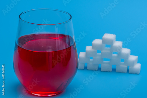 Szklanka z napojem obok piramida z cukru w kostkach 