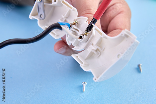 Assembly of folding electrical plug for an electrical cord, an electrician assembles plastic electric connector of European standard type f.