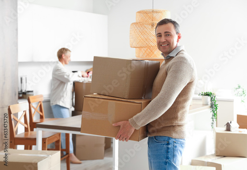 Mature man with cardboard boxes in kitchen on moving day
