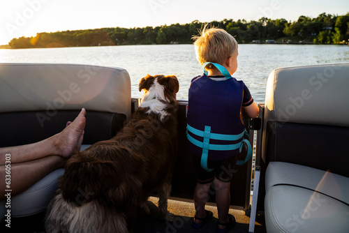 Blonde Toddler Boy Looking at Water on Boat with Family Dog
