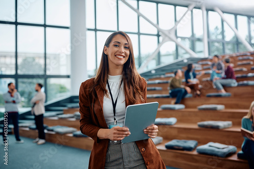 Happy businesswoman attending conference in convention center and looking at camera.