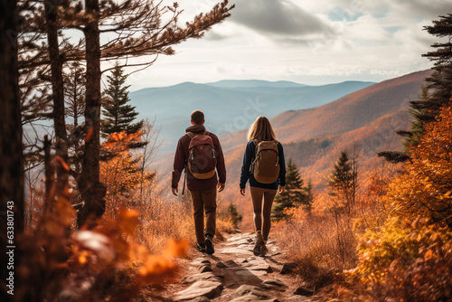 A couple hiking in the mountains with fall foliage in the blurred background 