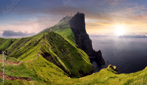 Sunset over green mountain with atlantic ocean, Faroe islands - Kallur lighthouse