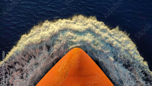 The bow of the ship cuts the waves at sunset