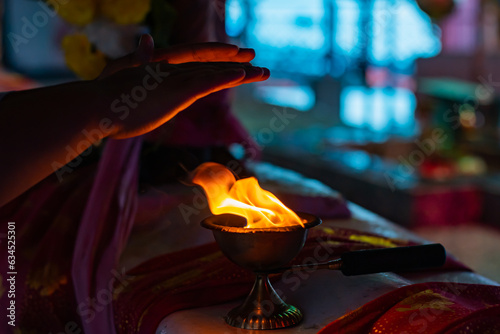 Holy fire of pradeep or oil lamp used in hindu puja. Hands of devotee seen taking blessings from the warmth of the holy flame as part of the aarti ritual.