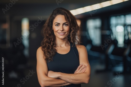 Portrait of smiling young woman standing with arms crossed in fitness center