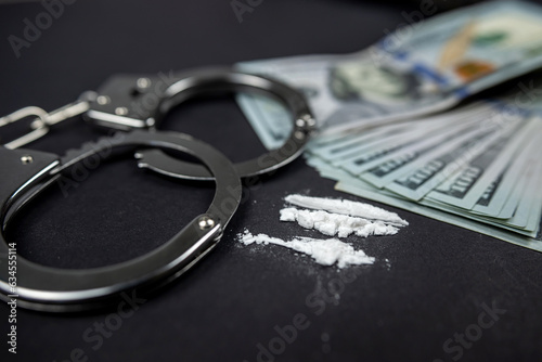 Plastic bags of cocaine or heroin and US dollar bills with handcuffs and bullets from a gun.