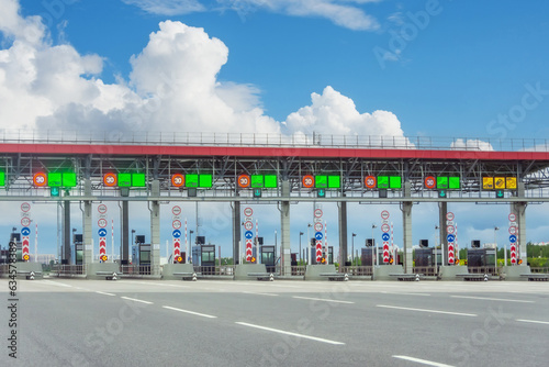View gate for cars at the entrance to the toll road, limited by the barrier. Cashless payment transponder, speed limit signs.