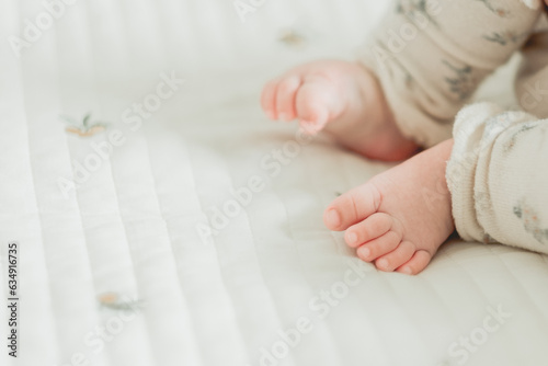 春の朝、マットで寝そべる日本人の赤ん坊のレッグウォーマーを着けた足