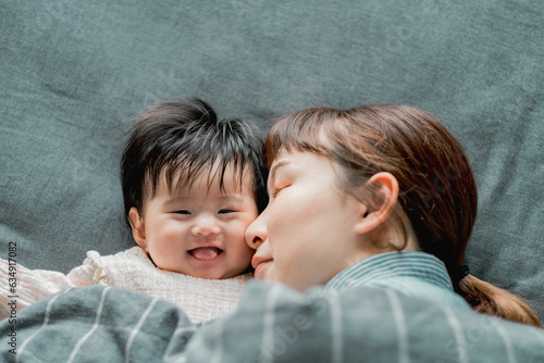 春の朝、ベッドで横たわって顔をくっつける日本人の母親と赤ちゃんの親子