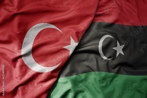 big waving national colorful flag of turkey and national flag of libya .