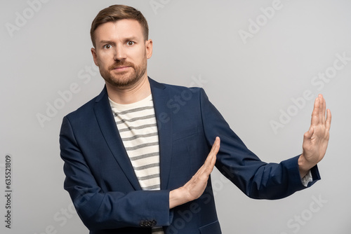 Frustrated man with disgust on serious face incredulously pushes away troubles with gesture of hands isolated on gray background. Male with angry expression refuse something bad showing denial.