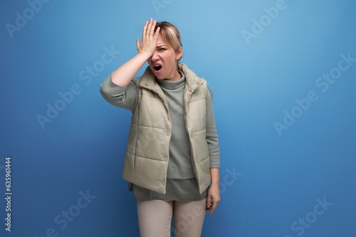 blonde 30s woman upset because of stupidity on studio blue background