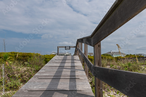 Wooden boardwalk from the beach to vacation home with private property sign, no trespassing.