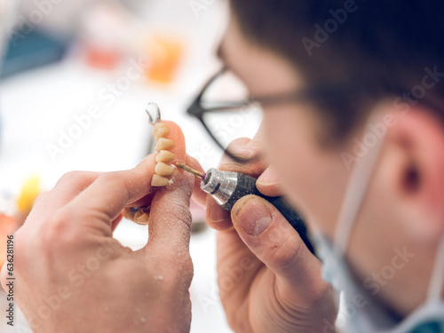 Crop dental technician man grinding denture with rotary machine