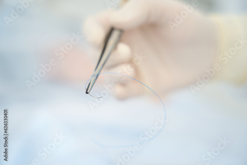 Surgeon holds in his hand a surgical needle