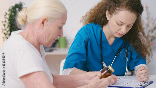 Female doctor prescribing medication to senior woman, regular home visit