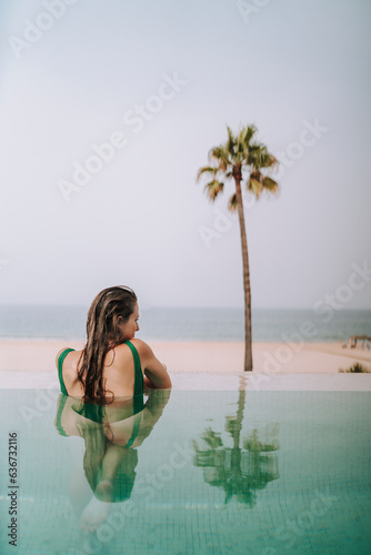 Chica joven delgada posando y descansando en piscina de hotel de lujo en andalucia