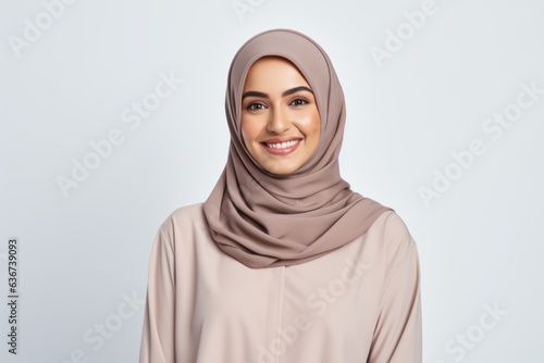 Portrait of a Saudi Arabian woman in her 30s in a white background wearing a cozy sweater