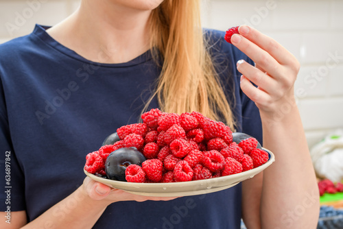 Kobieta jedząca czerwone maliny 