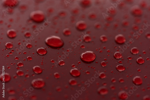 Rain droplets on red sports car surface with hydrophobic treatment