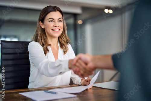 Happy mid aged business woman manager handshaking at office meeting. Smiling female hr hiring recruit at job interview, bank or insurance agent, lawyer making contract deal with client at work.