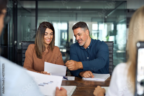 Professional executives business group working with documents at meeting in office. Smiling corporate board team having discussion planning company project strategy sitting at board room table.