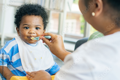 Mother raising take care an African-American Thai son feeds him simple and nutritious lunch : Portrait baby boy who enjoys eating food relishing and gluttonous.