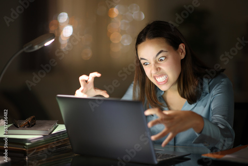 Angry teleworker using laptop in the night