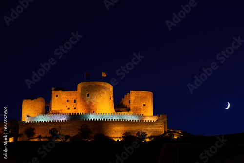 Night photo of the castle of Consuegra. Night landscape with the moon. Hill with mills and castle.