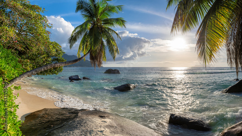 Panoramic view of beautiful beach at sunset with coconut palm tree, sea and beautiful rocks, Beau Vallon beach, Mahe island, Seychelles.