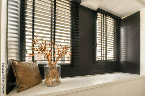 some flowers in a vase on a window sie with black shutters and white trim around the windowsill