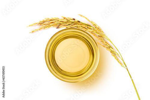 Glass bowl of rice bran oil extract with paddy on white . Top view